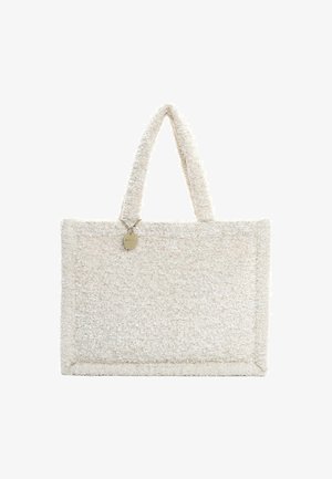 Sac fourre-tout en tissu crème doux et texturé avec deux poignées et un accent de tag en métal circulaire. Forme rectangulaire avec des bords cousus.