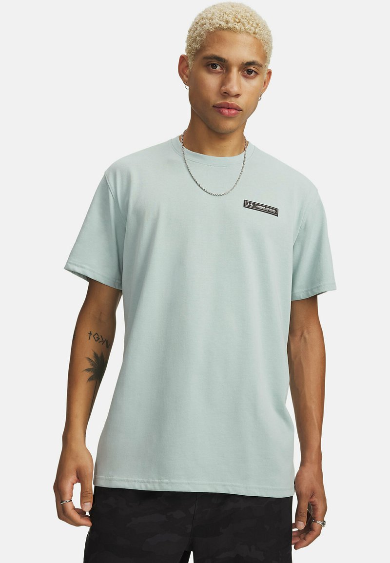 Lichtblauw katoenen T-shirt met korte mouwen, ronde hals en een zwarte labelaccent op de borst. Gestyled met donkere camoufleren shorts.