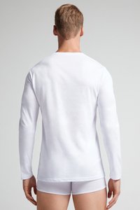 Witte lange mouwen shirt gemaakt van katoen, aansluitend ontwerp, gladde textuur, ronde hals, met een gelijkmatige zoom, gedragen met witte onderkleding.