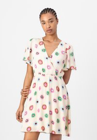 Floral wrap dress in cream with short sleeves, featuring multicolored flower patterns, a deep V-neck, and an elastic waistline.