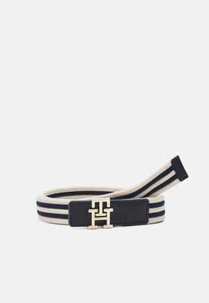 Ceinture en tissu rayé crème et marine avec une boucle double T dorée sur un patch en cuir.