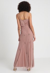 Maxi dress in dusty rose with spaghetti straps, embellished with vertical beadwork and floral designs, textured flowing fabric.