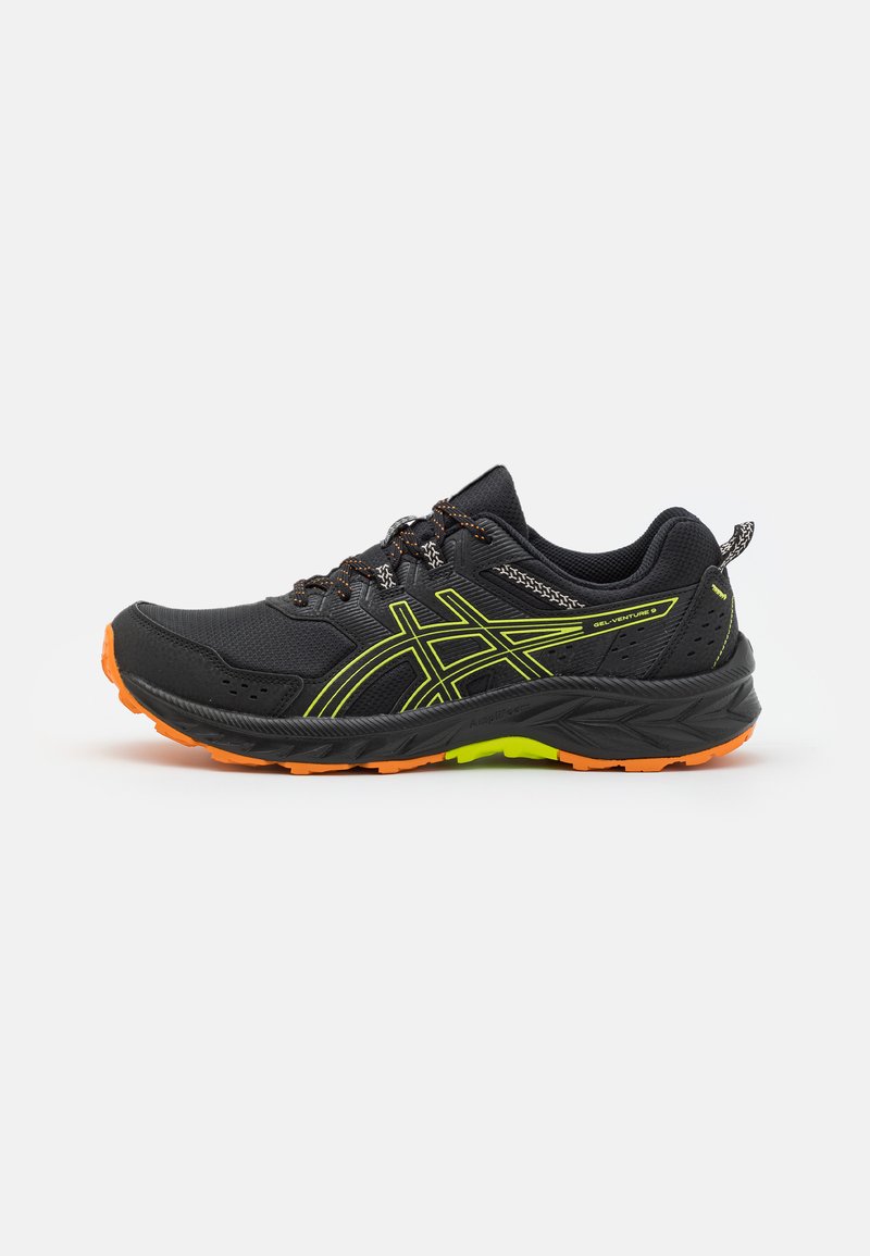 Scarpe da ginnastica nere con elementi verde neon, tomaia in tessuto testurizzato, suola in gomma arancione e dettagli riflettenti sui lati e sui lacci.
