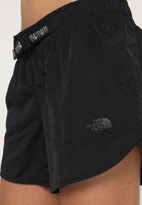 Mustat urheilushortsit, joissa on joustava vyötärö, sivutaskut ja musta "The North Face" -logo alahelassa.