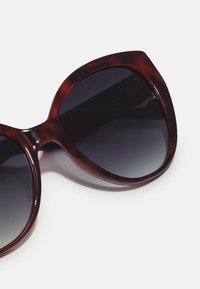 Gafas de sol de carey con montura grande y angular y lentes oscuros con degradado. Acabado brillante en el material plástico.