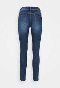 Jeans ajustados de mezclilla azul oscuro con una textura suave, cintura media y dos bolsillos traseros con acentos de costura.