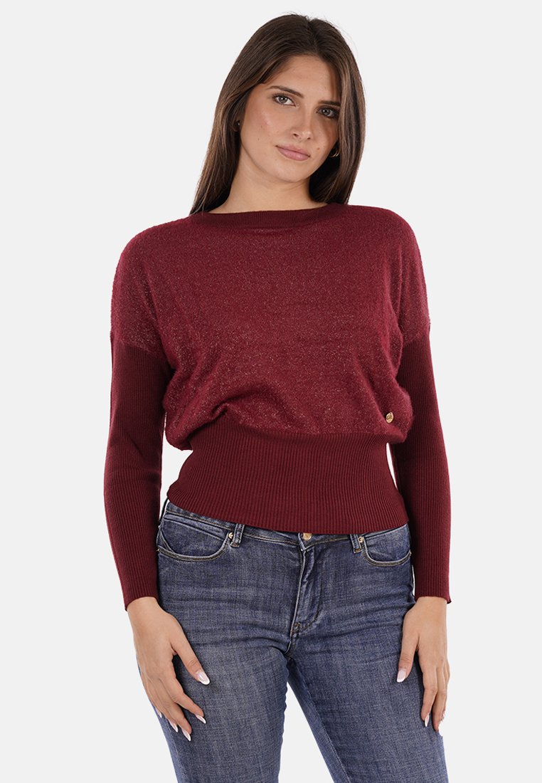 Maglione a maglia bordeaux con maniche lunghe, orlo a coste e una leggera trama scintillante. Si abbina a jeans in denim blu. Dettaglio dorato sul lato.