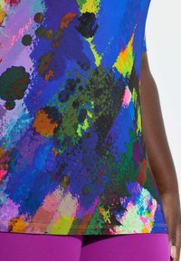 Multicolor sporttop met een levendig spetterpatroon, gemaakt van rekbare stof. Voorzien van paarse accenten aan de zoom.