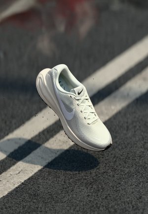 White running shoe with a mesh upper, rubber sole, and a prominent Nike swoosh. Features laces and a textured surface.