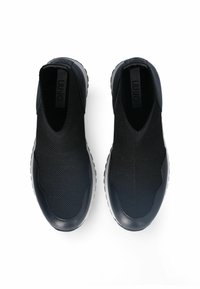 Scarpe slip-on nere con tomaia in maglia testurizzata, dettagli in pelle liscia e suola in gomma bianca spessa. Design minimalista. Senza lacci.
