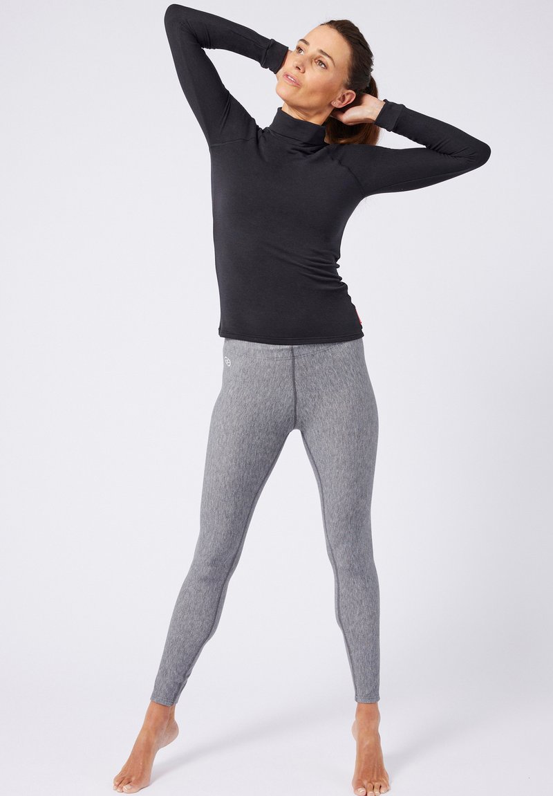 Zwarte lange mouwen top met een hoge kraag, gecombineerd met grijs gemêleerde leggings. De stof lijkt rekbaar, geschikt voor actieve kleding.