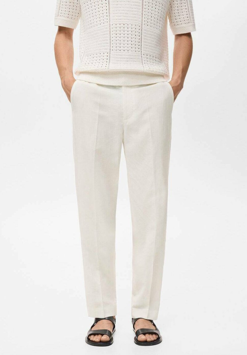 Cream-colored linen pants with a tailored fit and front crease, paired with a textured knit top and black flat sandals.