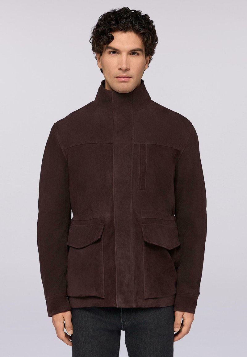Giacca in suede marrone con colletto alto, zip frontale e due grandi tasche a pattina. Texture liscia con finitura opaca e dettagli minimi.