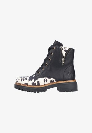 Bottine en cuir imprimé vache noir et blanc avec lacets sur le devant, fermeture éclair latérale, semelle cousue et petit talon épais.