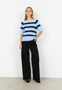 Világoskék és tengerészkék csíkos rövid ujjú pulóver, párosítva széles szárú fekete nadrággal, amely kontrasztos varrással és laza szabással rendelkezik.