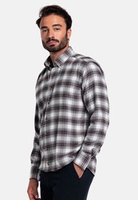 Bruine en blauwe geruite flanellen shirt met een button-down kraag en lange mouwen, met een relaxte pasvorm en voorzakken.