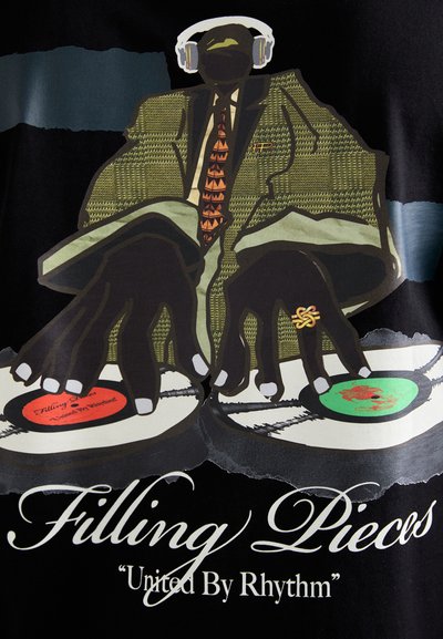 Black t-shirt featuring a graphic illustration of a figure in a patterned green blazer, red tie, and headphones, DJing with vinyl records.
