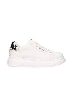 Zapatilla de cuero blanca con puntera redondeada, suela plana blanca y ojales dorados; el diseño presenta un estampado de vaca en blanco y negro en el talón.