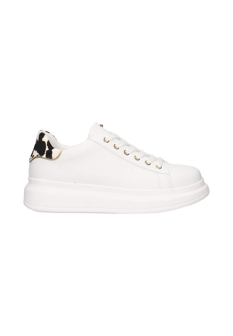 Zapatilla de cuero blanca con puntera redondeada, suela plana blanca y ojales dorados; el diseño presenta un estampado de vaca en blanco y negro en el talón.
