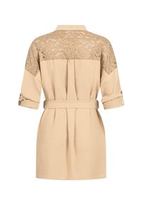 Knee-længde, beige kjole med en blonde ryg, tætsiddende ærmer og et bælte. Glat stof med strukturerede blonder detaljer.