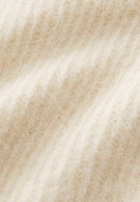 Primo piano di un tessuto morbido color crema, peloso, con fibre sottili e una sottile texture a coste.