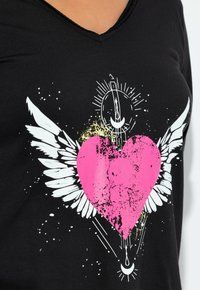 Schwarzes Baumwoll-T-Shirt mit V-Ausschnitt, das eine große pinke Herzgrafik, weiße Flügel und gelbe Spritzerakzente zeigt.