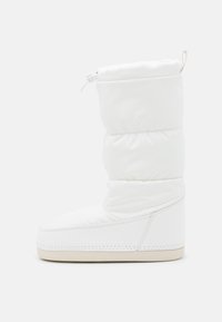 Botte blanche rembourrée avec une texture lisse, un bout arrondi et une semelle crème contrastante. Inclut un haut resserré avec une poignée.