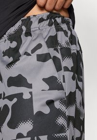Γκρι καμουφλάζ σορτς με ελαστική μέση με σούρα, γωνιώτρες τσέπες και υφή με διάφορα μαύρα μοτίβα.