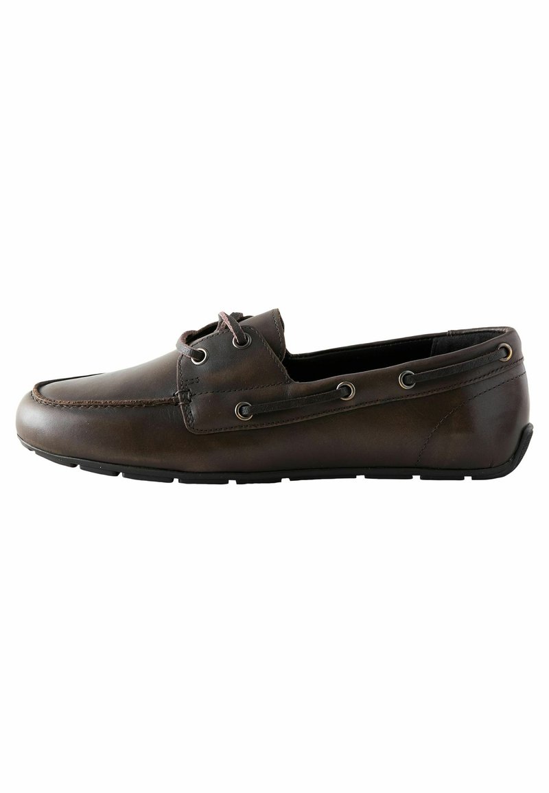 Chaussure bateau en cuir marron avec bout arrondi, détail de couture et œillets métalliques. Dispose d'une semelle en caoutchouc plate pour la traction et le confort.