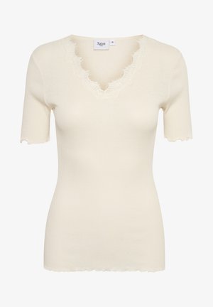 Krém színű bordázott póló V nyakkal és hullámos szélekkel. Rövid ujjú, testhezálló fazon, puha tapintás. A címke olvasható: "Saint."