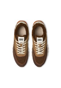 Baskets en suede marron avec des accents beiges, dotées d'une doublure en fourrure texturée, de lacets blancs et d'une semelle en caoutchouc épaisse. Étiquette de marque sur la languette.