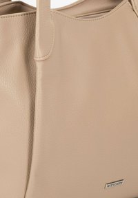 Beige leren tote bag met een gladde textuur en een gestructureerde vorm. Beschikt over lange handvatten en een subtiele metallic logo-accent.
