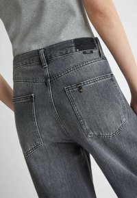 Grijze denim jeans met een rechte pasvorm, voorzien van achterzakken en een klein merkteken op de tailleband, met een licht versleten textuur.