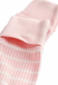 Chaussettes rayées roses avec une texture côtelée, dotées d'un revers et de subtils rayures blanches. Matière en coton douce.