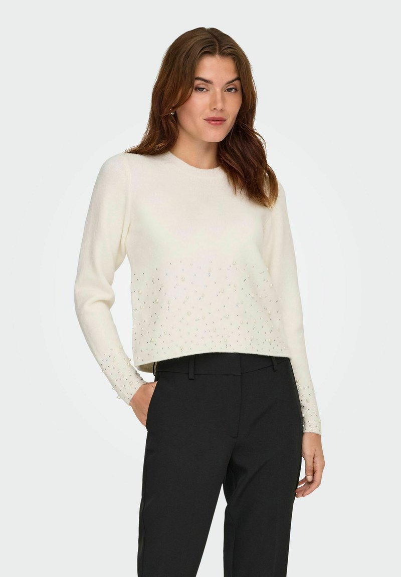 Maglione color crema con un design cropped, caratterizzato da un motivo decorativo di perline iridescenti lungo il fondo e le maniche.