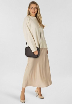 Cremefarbener Strickpullover, beiger Satinhrock und nudefarbene High Heels. Schwarze Umhängetasche mit glatter Textur und minimalistischem Design.