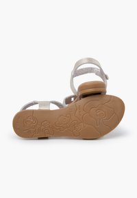 Silver metallic sandals with a textured upper, a low heel, and a floral pattern on the brown rubber sole. Non-slip design with adjustable straps.