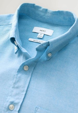 Light blue button-up shirt with a regular fit, made from fabric with a subtle texture. Features a classic collar and white buttons.