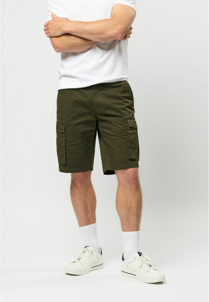 Pantaloni scurți cargo de culoare verde măsliniu, cu multiple buzunare, fabricați dintr-un material ușor. Asortați cu un tricou alb și adidași albi.