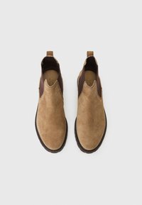Brune ruskinds Chelsea støvler med elastiske sidepaneler, slip-on design og strukturerede gummisåler. Syning detaljer langs kanterne.