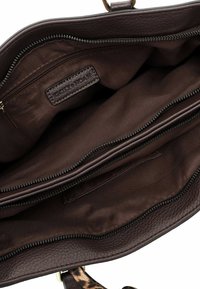 Brown leather handbag interior featuring two zippered compartments, smooth fabric lining, and a label with "Emily & Noah."