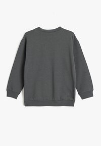 Sudadera gris de manga larga, con cuello y puños de canalé, fabricada en un tejido suave y con un corte relajado. Sin logotipos ni patrones visibles.