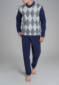 Set di abbigliamento informale di colore blu navy, composto da una felpa a motivi con design a diamante in grigio, bianco e rosso, abbinata a pantaloni blu navy semplici.