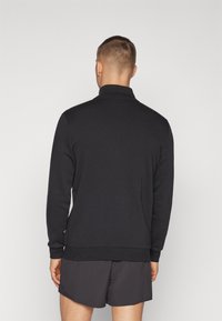 Black pullover sweatshirt with a high collar, made from a soft fabric, featuring long sleeves and a fitted waistband.