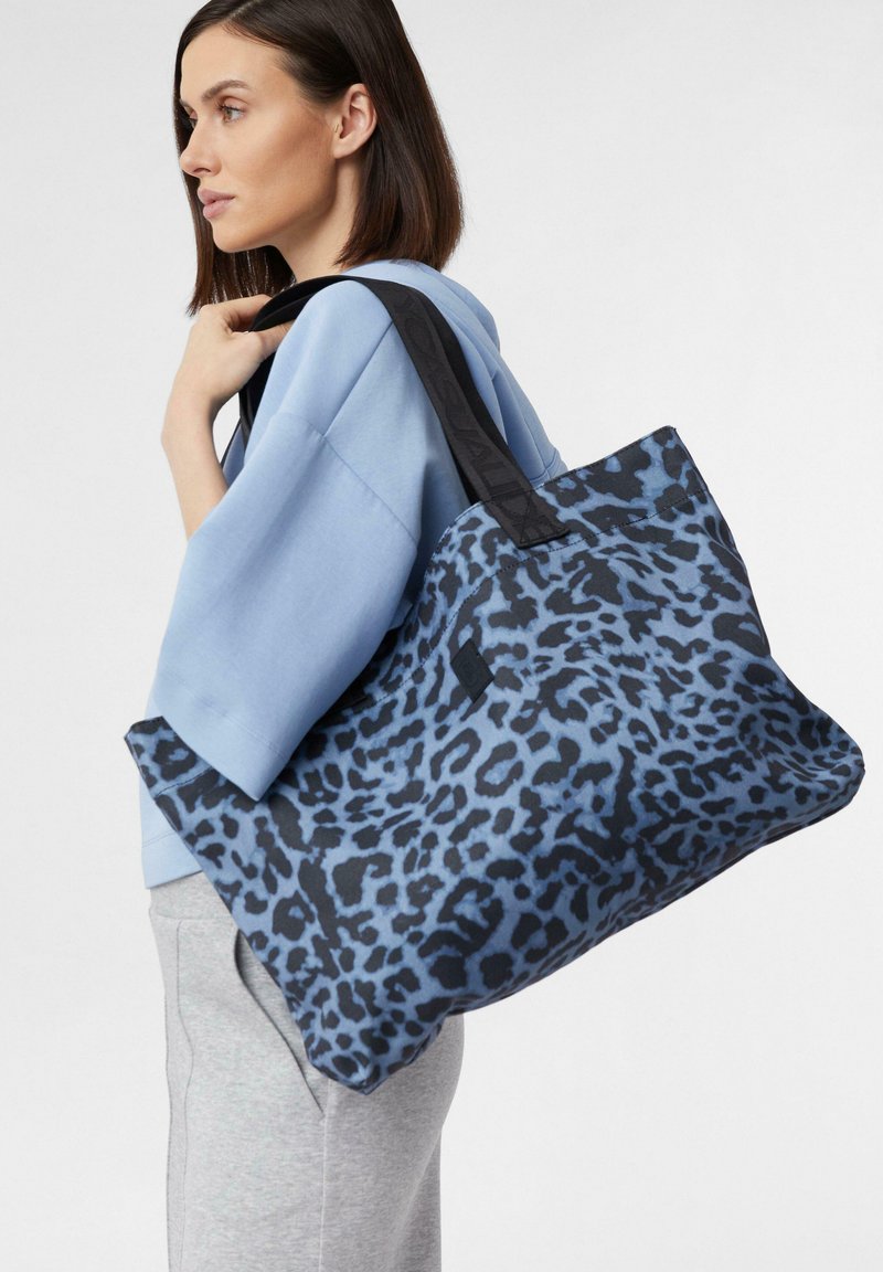 Borsa a tracolla con stampa leopardata blu e manici neri, realizzata in tessuto resistente, con un design spazioso e una consistenza liscia.