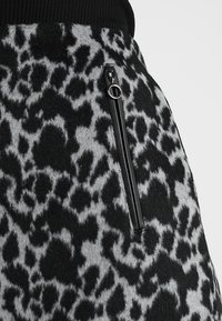 Black and gray leopard print fabric with vertical black zipper pocket featuring silver ring pull tab.