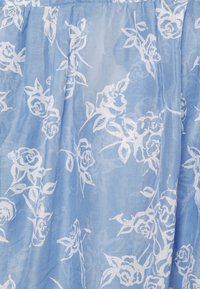 Tecido azul claro, transparente, com um padrão floral em branco, apresentando rosas estilizadas e folhas. Textura suave com um caimento fluido.