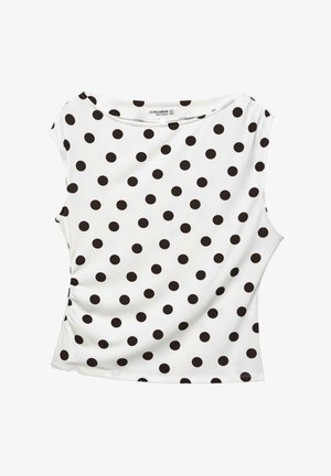 Top alb fără mâneci, cu buline negre mari dispuse uniform și o cusătură laterală ușor adunată.