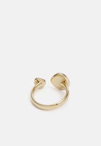 Anello in metallo dorato con un design aperto che presenta estremità arrotondate, superficie liscia e finitura lucida, che mette in risalto uno stile minimalista.
