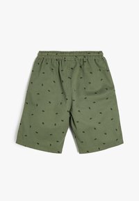 Olijfgroene shorts met een elastische tailleband, versierd met kleine zwarte bladvormen die gelijkmatig over de stof zijn verspreid.